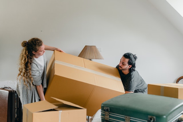 two people carrying large box into their new rental property